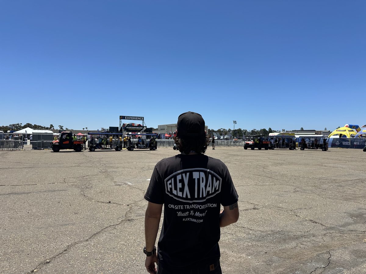 FlexTram crew member in a branded shirt overlooking the deployed fleet at an event