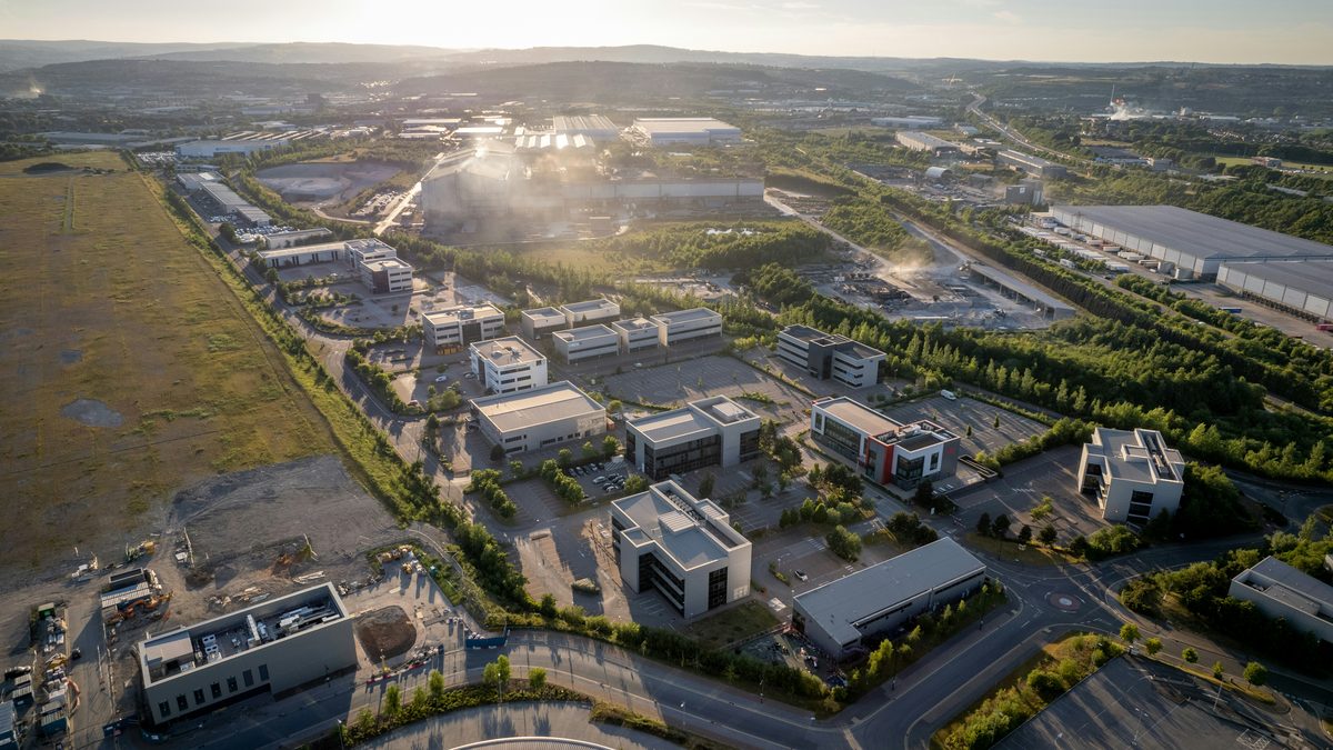 Aerial view at sunset of a sprawling industrial and data center campus with multiple large buildings, parking lots, and access roads spread across hundreds of acres