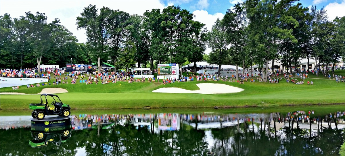 Golf tournament venue with spectators gathered around green and sand traps