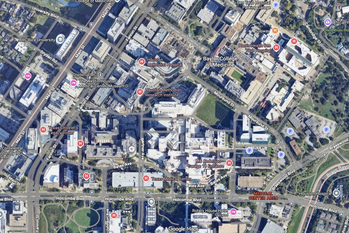Aerial view of Texas Medical Center in Houston with multiple hospital buildings, parking garages, and pedestrian corridors across a sprawling medical campus