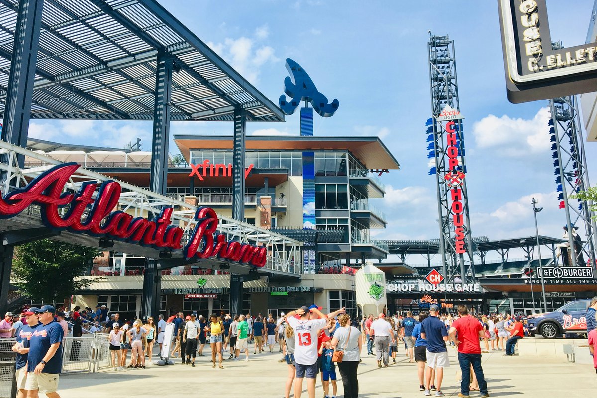 Atlanta Braves Battery district mixed-use development with stadium signage, restaurants, and crowds of fans walking through the entertainment plaza on a sunny afternoon